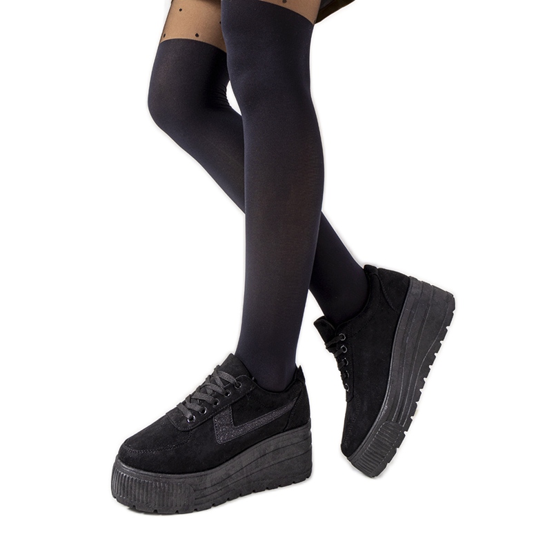 Schwarze Turnschuhe auf einer hohen botanischen Sohle