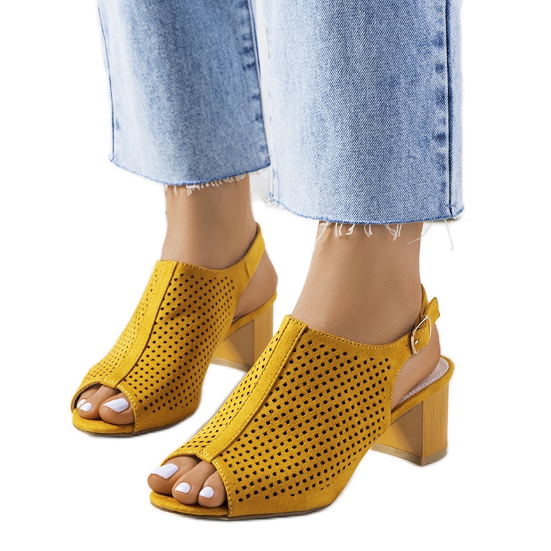 Gelbe durchbrochene Sandalen an einem Belinda-Pfosten