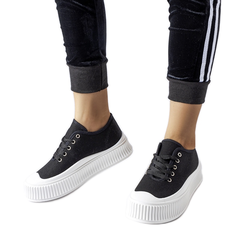 Schwarze Turnschuhe auf einem dicken weißen Rina-Plateau