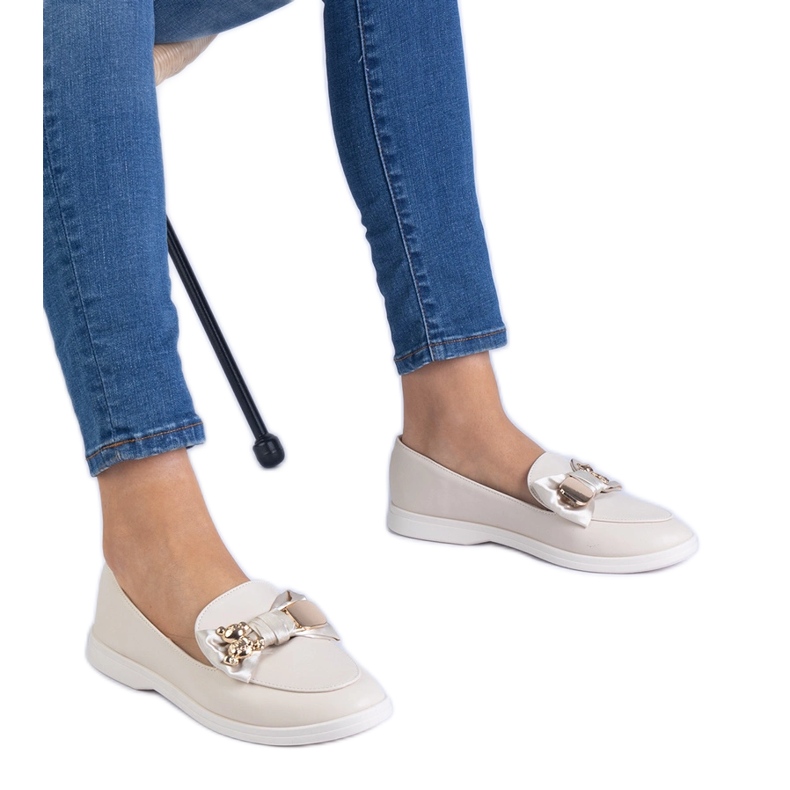 Beige -Slipper mit einem Bug und einem goldenen Teddybär dekoriert