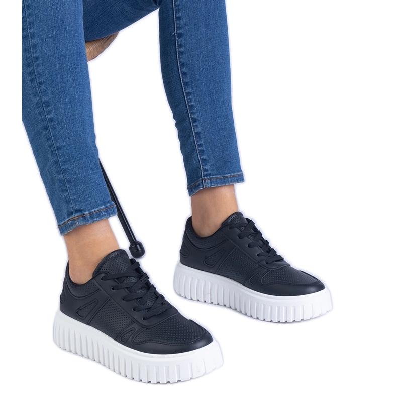 Schwarze Openwork -Turnschuhe auf einer massiven Sohle