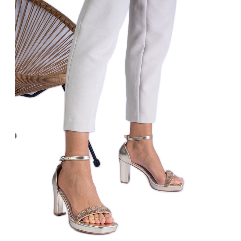 Golden elegante Sandalen auf der Säule mit Zirkonen