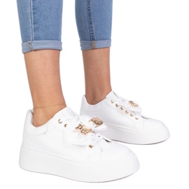 Weiße Turnschuhe mit einem Bug und einem goldenen Teddybär dekoriert