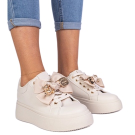 Beige Sneakers mit einem Bug und einem goldenen Teddybär dekoriert