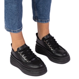 Schwarze Frauen -Turnschuhe auf einer hohen Sohle
