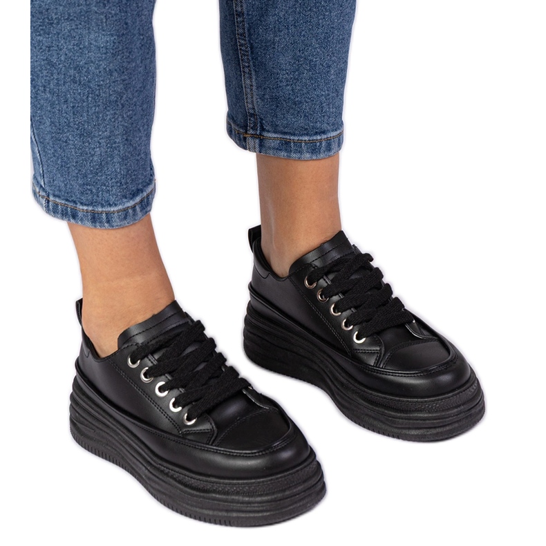 Schwarze Frauen -Turnschuhe auf einer hohen Sohle