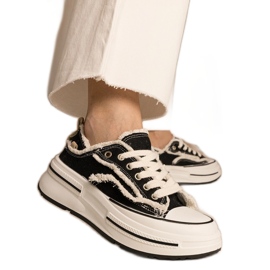 Schwarze Frauen -Turnschuhe auf einer hohen Sohle