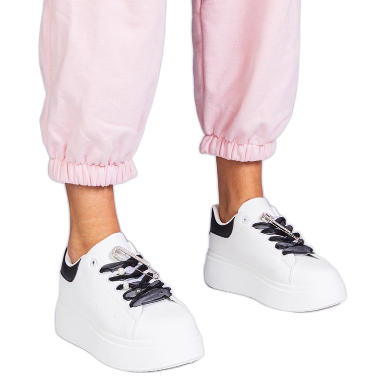 Weiße Turnschuhe mit einem schwarzen Einsatz und einem Zirkonstift