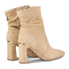 Beigefarbene Damenstiefel auf einem verzierten Pfosten 1