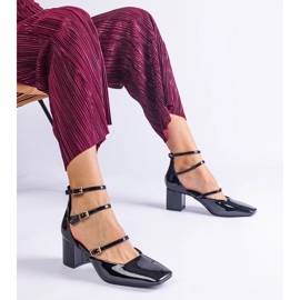 Schwarze Pumpen, die auf einem Pfosten mit Schnallen lackiert sind 1