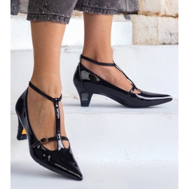 Schwarze Pumpen, die auf einem niedrigen Stapel mit Schnallen lackiert sind 1