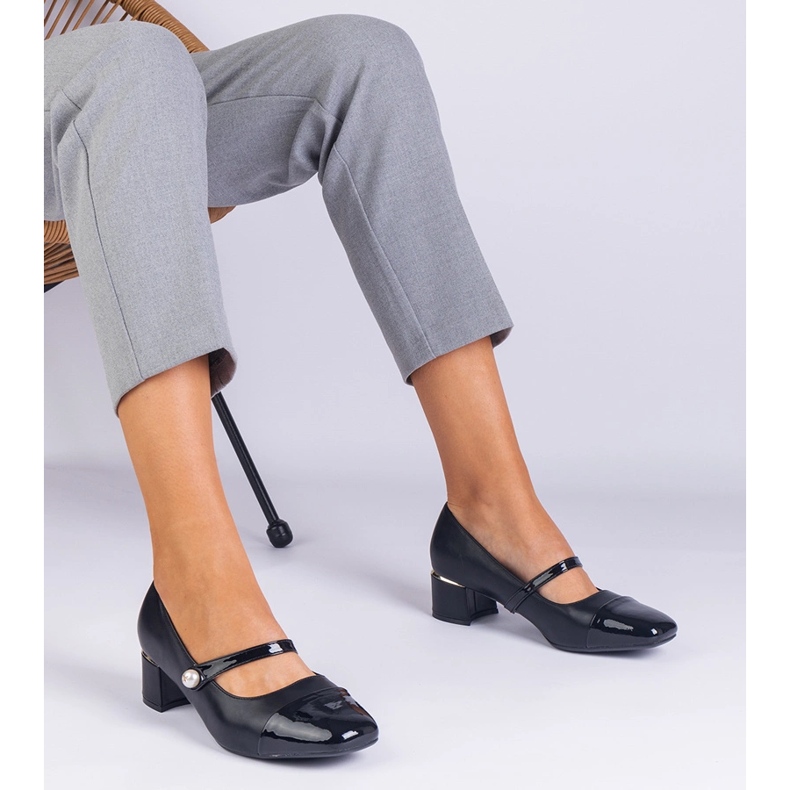 Schwarze Pumpen auf dem Pfosten mit einem lackierten Zeh 1