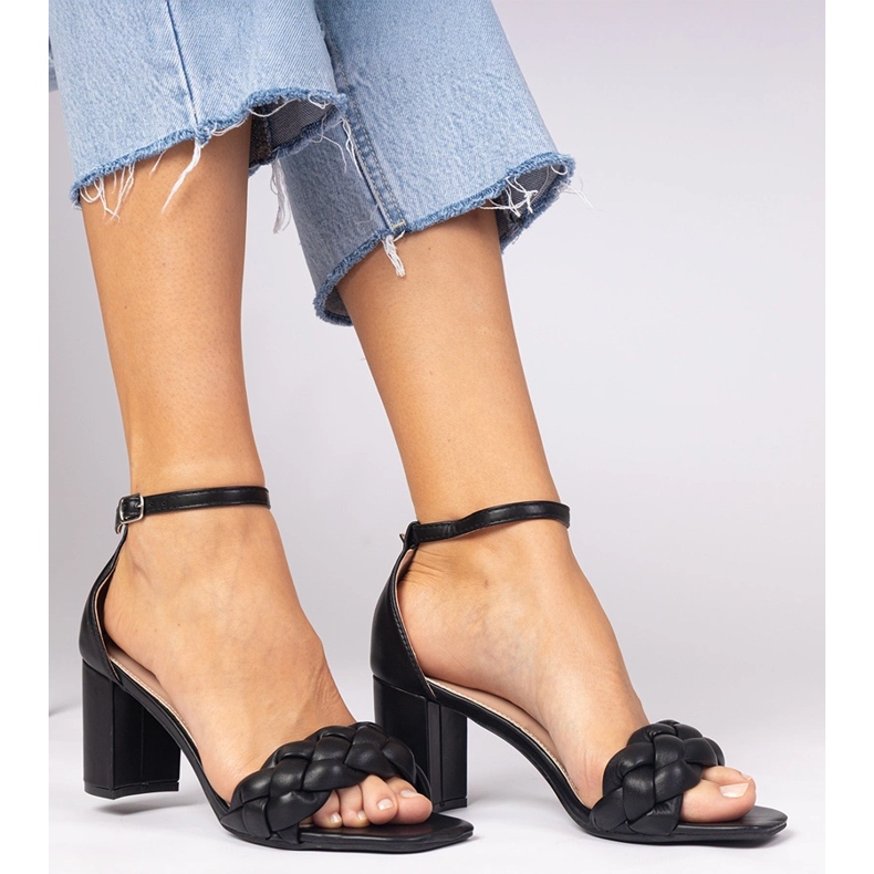 Schwarze Sandalen auf dem Pfosten bedeckt 1