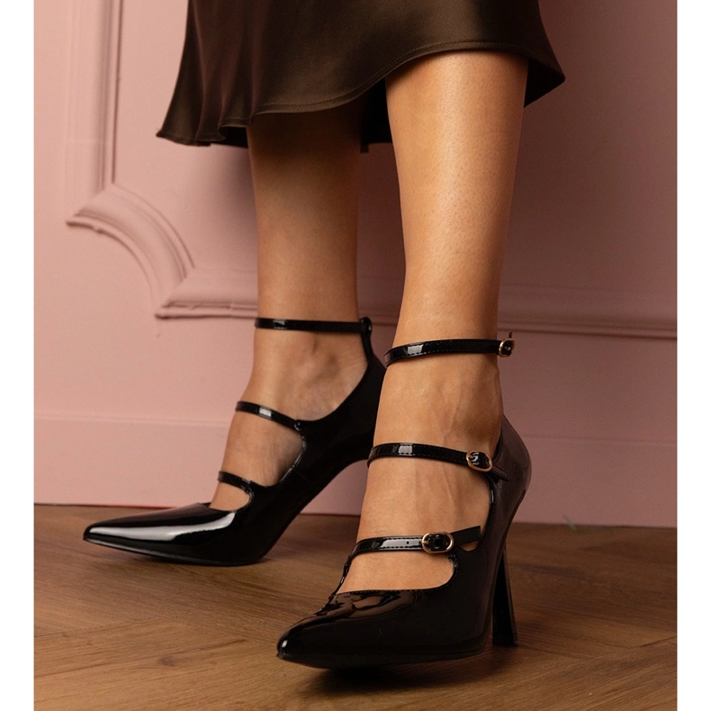 Schwarze Pumpen, die auf einem Stift mit Schnallen lackiert sind 1