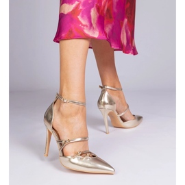 Goldene Pumpen auf einem hohen Absatz, der am Knöchel befestigt ist 1