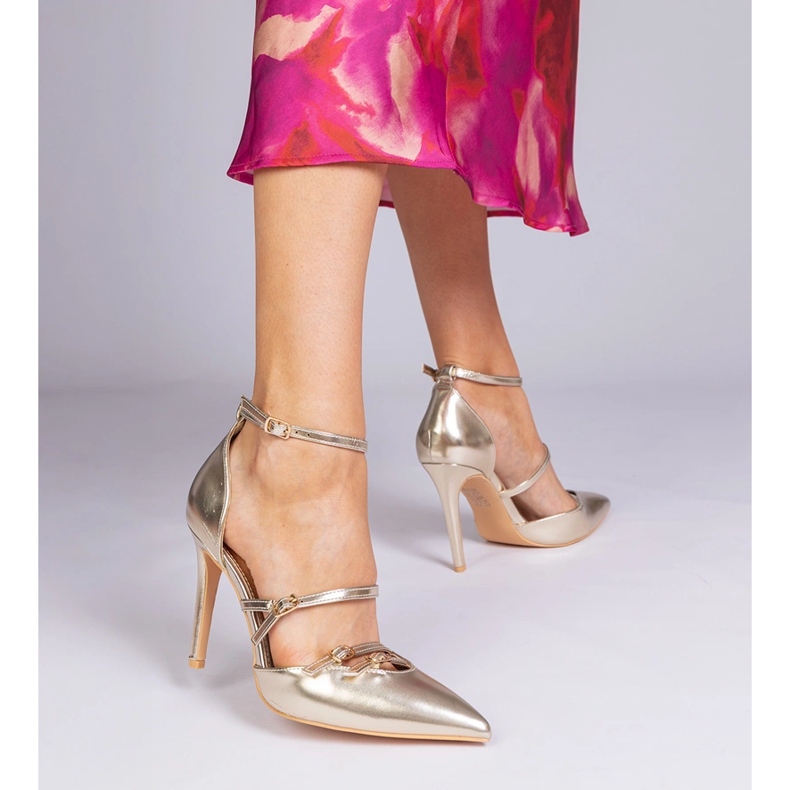 Goldene Pumpen auf einem hohen Absatz, der am Knöchel befestigt ist 1