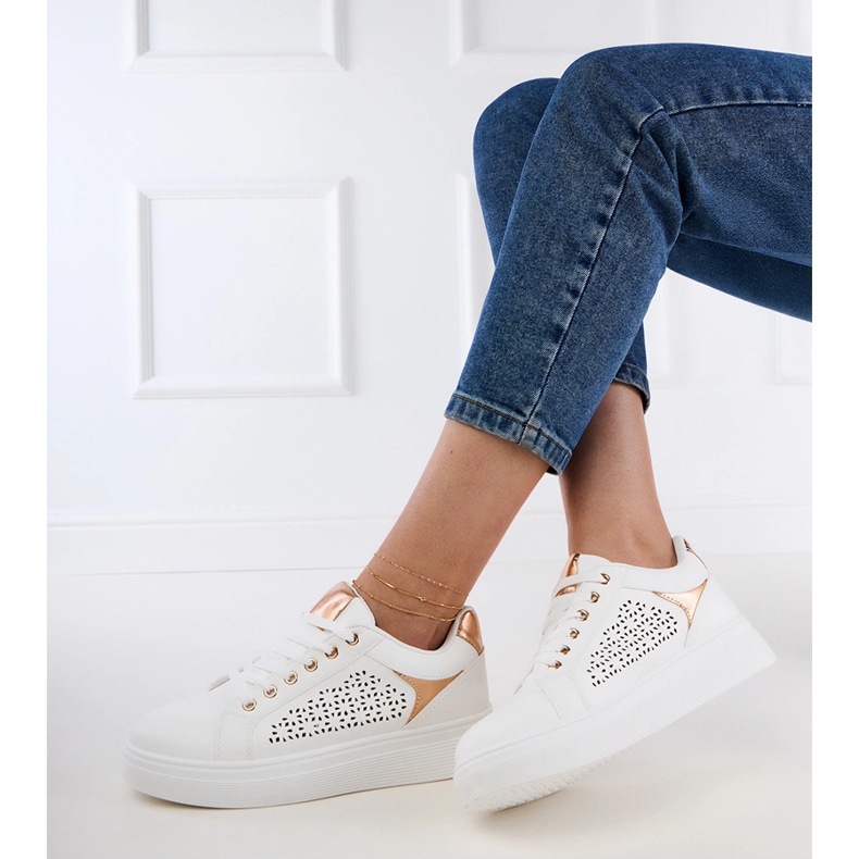 Weiße Turnschuhe mit goldenen Einsätzen auf der Plattform 2