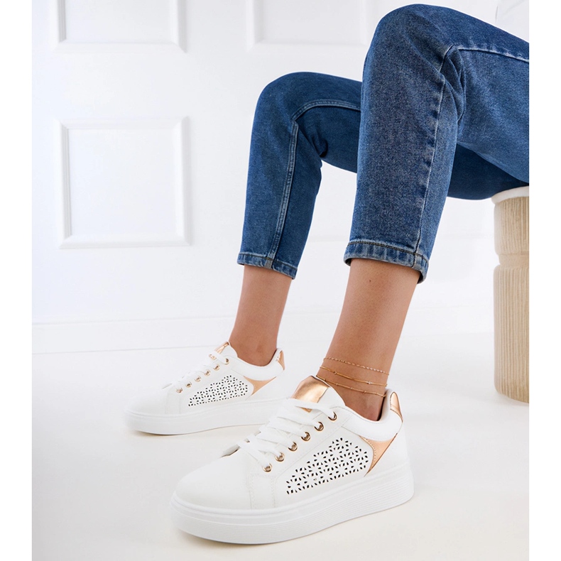 Weiße Turnschuhe mit goldenen Einsätzen auf der Plattform 1