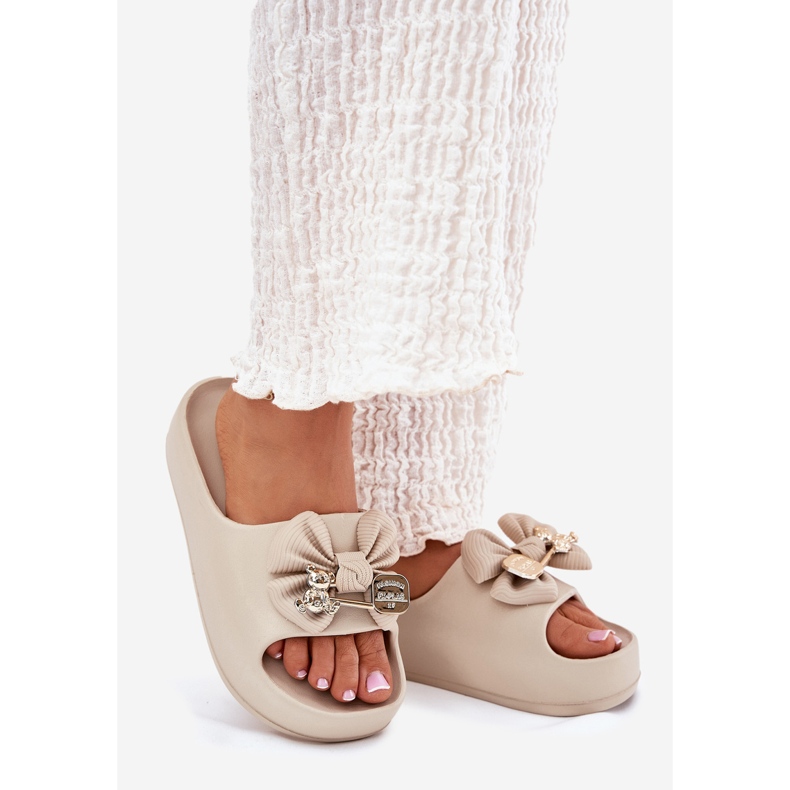 Frauenschaumflip flops auf der Plattform mit einem Bug und einer dunklen beige Brosche 1