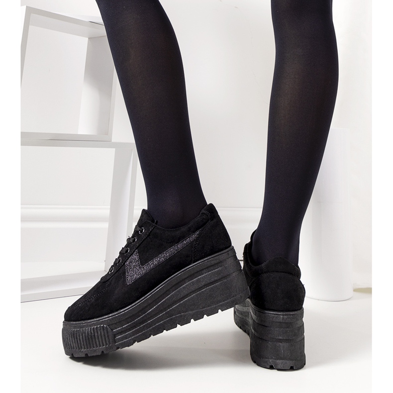 Schwarze Turnschuhe auf einer hohen botanischen Sohle 1